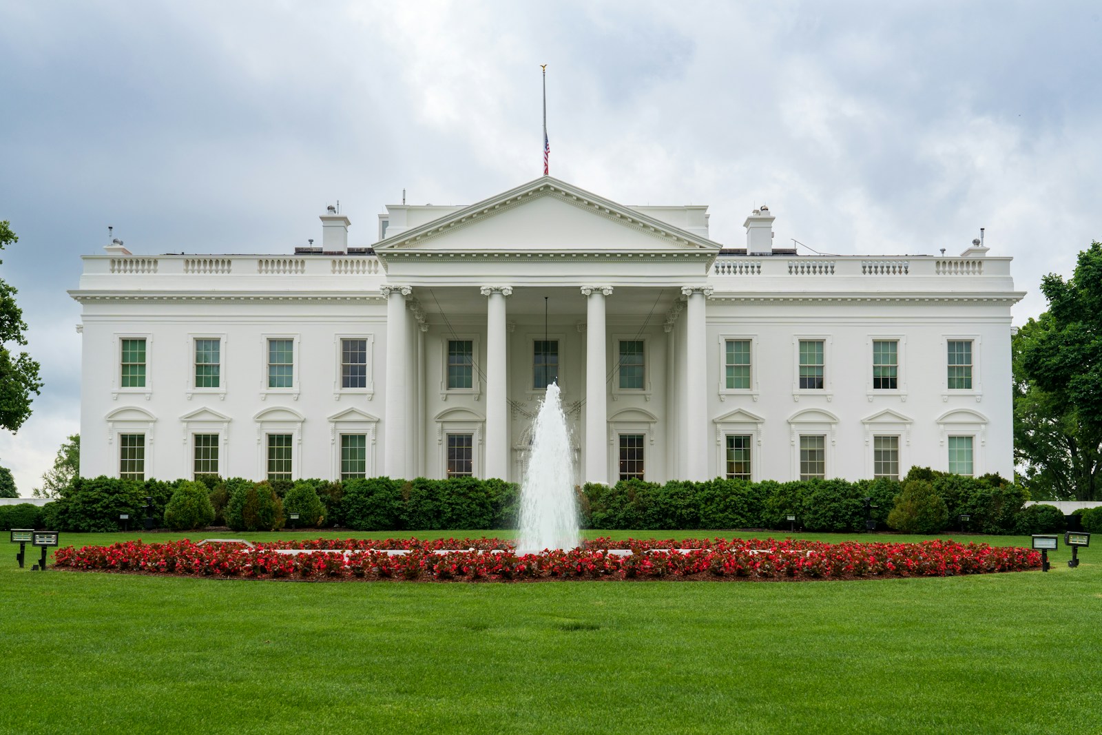 A large white building with a fountain in front of it